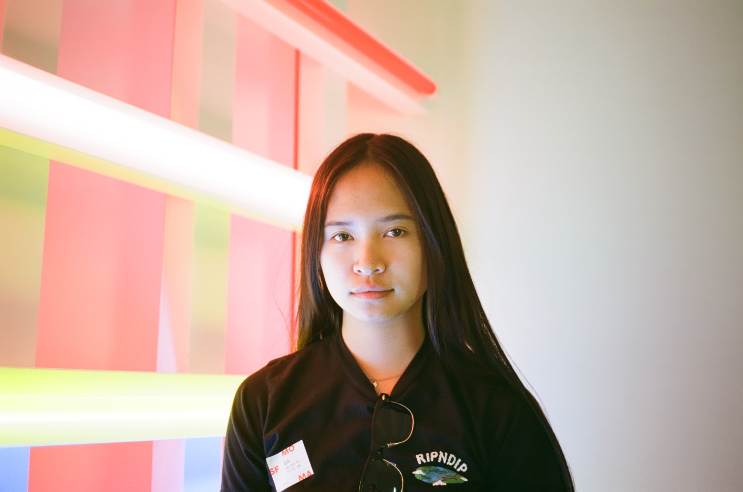 A portrait of a woman beside luminous coral, green, and white light installations.